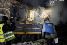 Prokur&aacute;tor pre vojnov&eacute; zločiny a policajt pracuj&uacute; vedľa osobn&eacute;ho vlaku zasiahnut&eacute;ho rusk&yacute;m dronom v Charkovskej oblasti na Ukrajine. FOTO: REUTERS