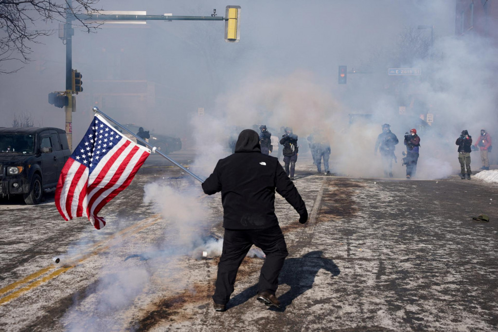Osoba drž&iacute; americk&uacute; vlajku počas stretov medzi feder&aacute;lnymi agentmi a členmi komunity na mieste činu, kde feder&aacute;lni agenti smrteľne postrelili muža v Minneapolise. FOTO: Reuters