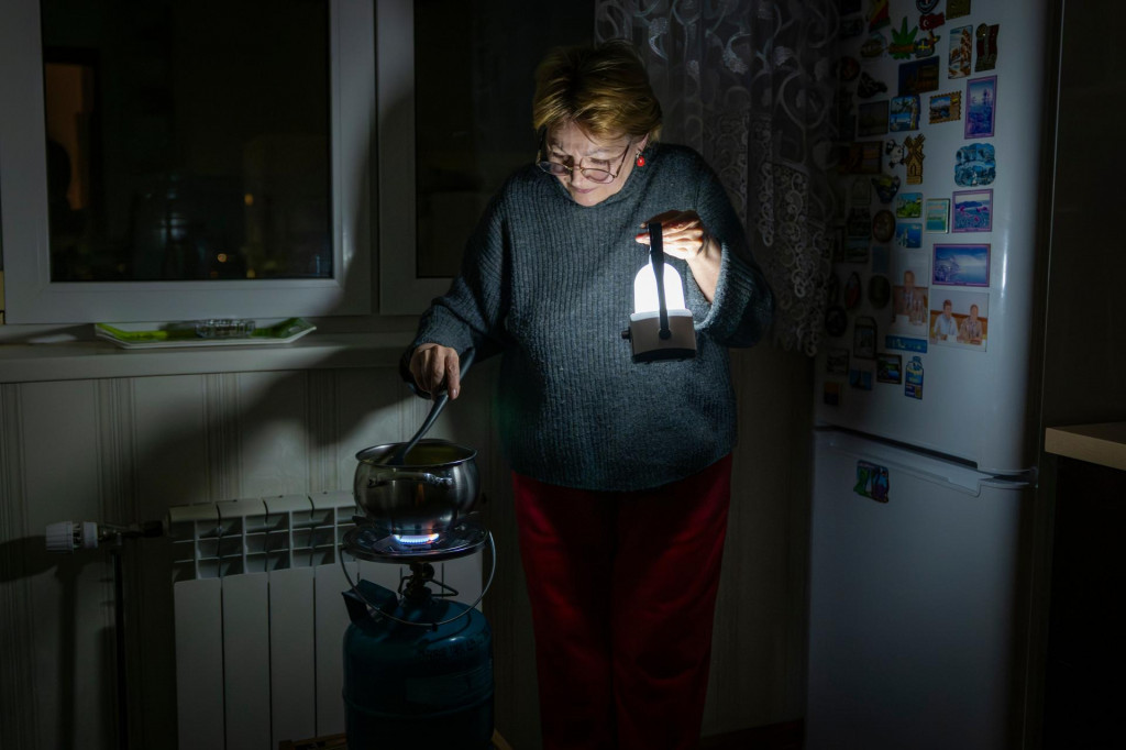 Žena var&iacute; jedlo na plynovom spor&aacute;ku pri svetle lamp&aacute;&scaron;a po rusk&yacute;ch &uacute;tokoch na ukrajinsk&uacute; energetick&uacute; infra&scaron;trukt&uacute;ru v Kyjeve. FOTO: TASR/AP