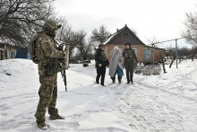 Policajti pom&aacute;haj&uacute; obyvateľovi počas evaku&aacute;cie z dediny v prvej l&iacute;nii. FOTO: Reuters