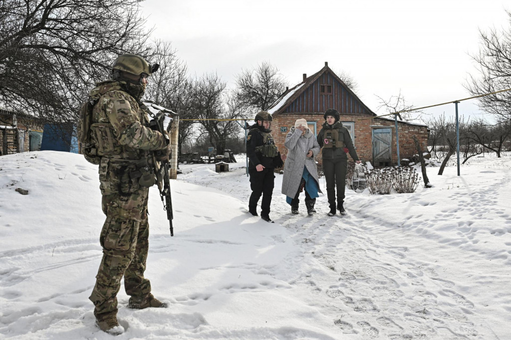 Policajti pom&aacute;haj&uacute; obyvateľovi počas evaku&aacute;cie z dediny v prvej l&iacute;nii. FOTO: Reuters
