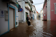 Dobrovoľn&iacute;k nesie psa na zaplavenej ulici po b&uacute;rke Leo v Portugalsku. FOTO: Reuters