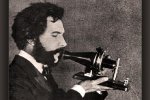 Herec stv&aacute;rňuj&uacute;ci Alexandra Grahama Bella hovoriaceho do ran&eacute;ho modelu svojho telef&oacute;nu. Sn&iacute;mka poch&aacute;dza z propagačn&eacute;ho filmu spoločnosti American Telephone & Telegraph Company natočen&eacute;ho v roku 1926, pri pr&iacute;ležitosti 50. v&yacute;ročia vydania patentu na telef&oacute;n.