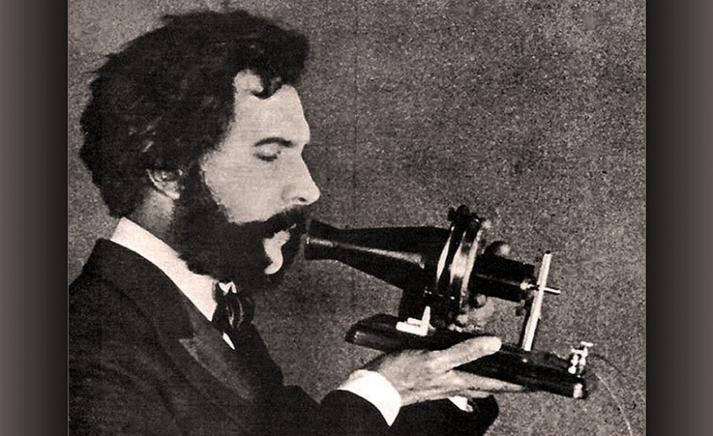 Herec stv&aacute;rňuj&uacute;ci Alexandra Grahama Bella hovoriaceho do ran&eacute;ho modelu svojho telef&oacute;nu. Sn&iacute;mka poch&aacute;dza z propagačn&eacute;ho filmu spoločnosti American Telephone & Telegraph Company natočen&eacute;ho v roku 1926, pri pr&iacute;ležitosti 50. v&yacute;ročia vydania patentu na telef&oacute;n.