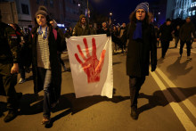 Ľudia držia transparent počas protestu v Novom Sade. FOTO: Reuters