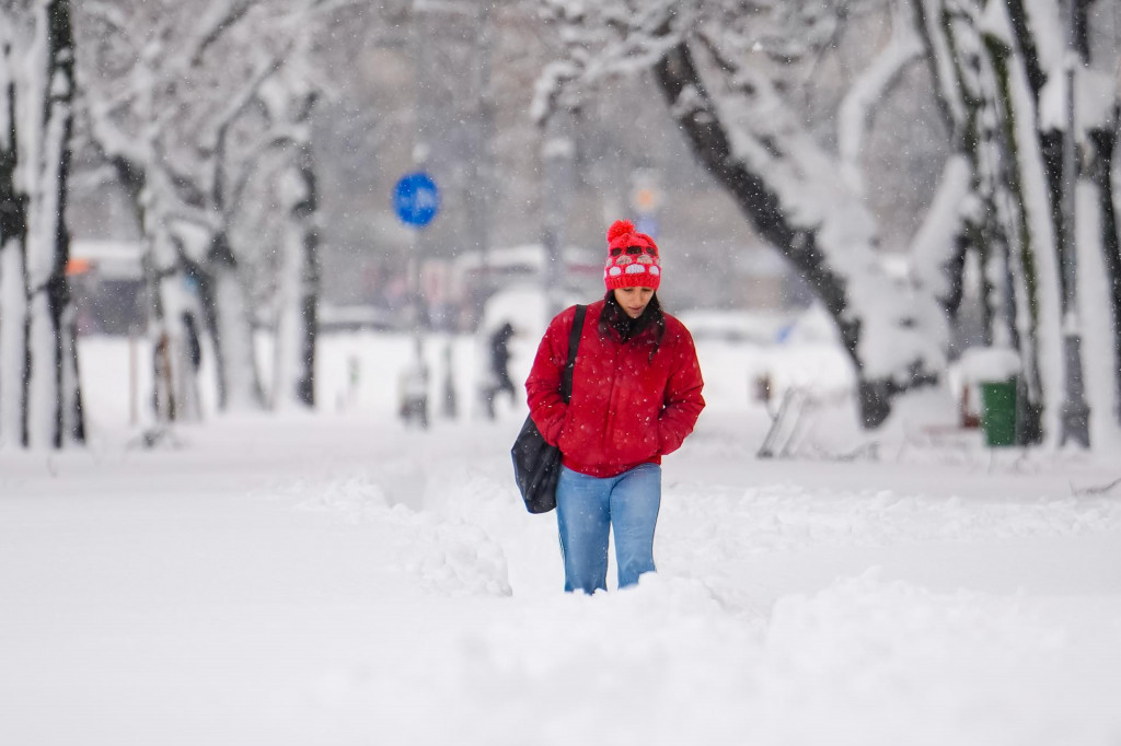 Žena sa brod&iacute; snehom po snehovej b&uacute;rke v Bukure&scaron;ti. FOTO: TASR/AP