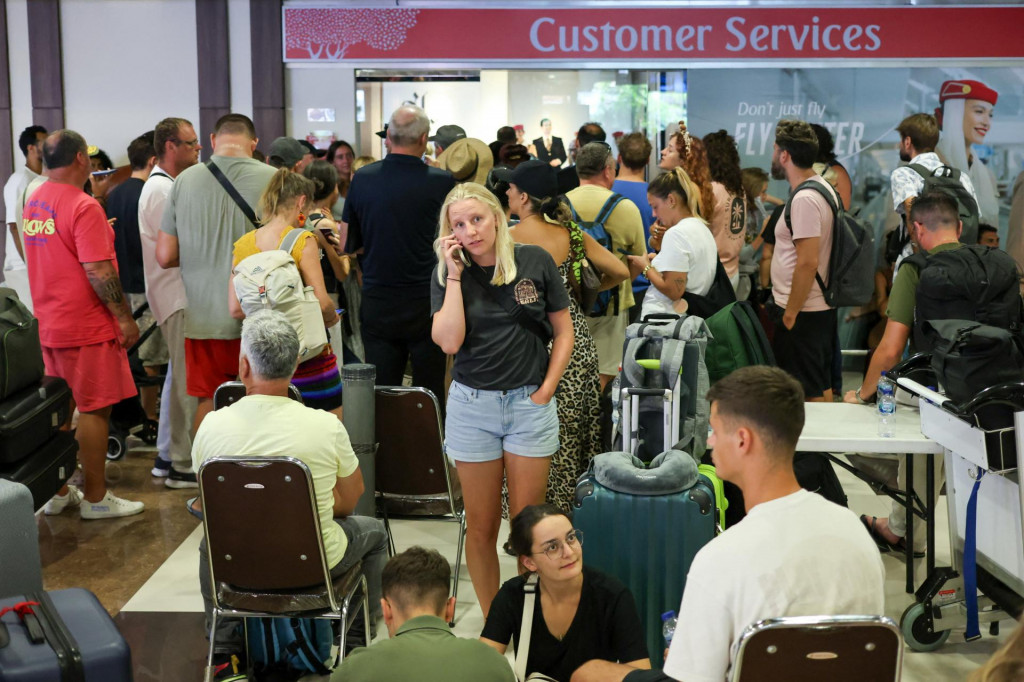 Uviaznut&iacute; cestuj&uacute;ci čakaj&uacute; v bl&iacute;zkosti kancel&aacute;rie z&aacute;kazn&iacute;ckeho servisu spoločnosti Emirates Airways na medzin&aacute;rodnom letisku I Gusti Ngurah Rai po zru&scaron;en&iacute; letov do Dauhy, Dubaja a Ab&uacute; Zab&iacute; po &uacute;tokoch Spojen&yacute;ch &scaron;t&aacute;tov a Izraela na Ir&aacute;n. FOTO: REUTERS
