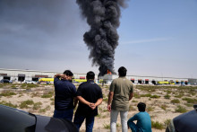 Ľudia sleduj&uacute; ako plamene a čierny dym st&uacute;paj&uacute; zo skladu v priemyselnej z&oacute;ne &Scaron;arjah City počas odvetn&eacute;ho &uacute;toku Ir&aacute;nu v Dubaji 1. marca 2026. TASR. FOTO TASR/AP