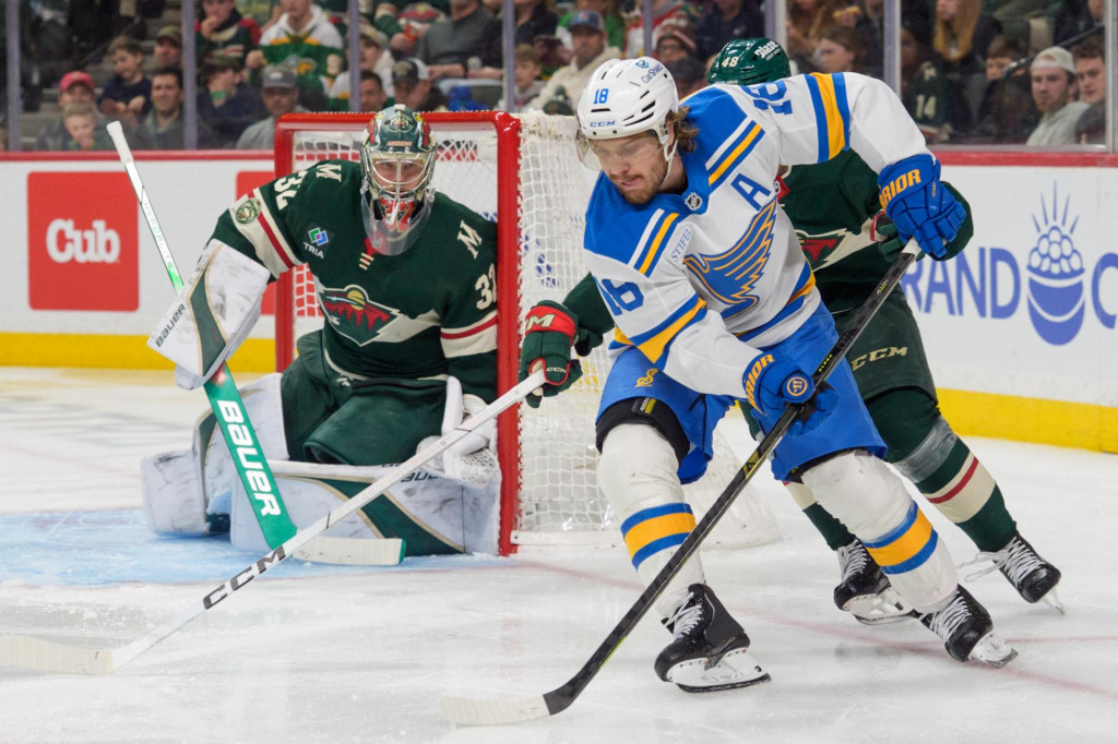 Center St. Louis Blues Robert Thomas (18) sa v tretej tretine pok&uacute;&scaron;a o obrann&uacute; akciu okolo brank&aacute;ra Minnesota Wild Filipa Gustavssona (32). FOTO: Matt Blewett/Imagn Images