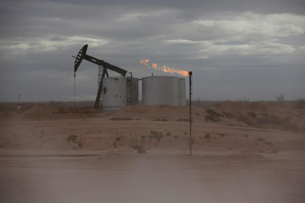 FILE PHOTO: Dust blows around a crude oil pump jack and flare burning excess gas at a drill pad in the Permian Basin in Loving County, Texas, U.S. November 25, 2019. Picture taken November 25, 2019. REUTERS/Angus Mordant/File Photo FOTO: Angus Mordant