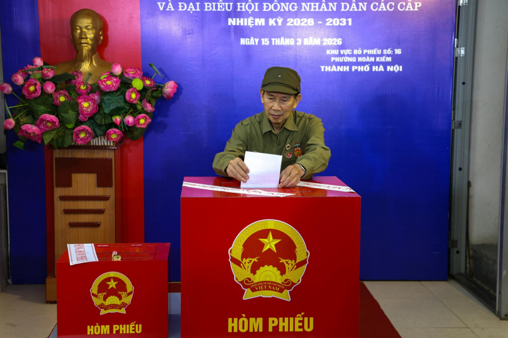 Muž odovzd&aacute;va svoj hlasovac&iacute; l&iacute;stok vo volebnej miestnosti počas parlamentn&yacute;ch volieb v Hanoji vo Vietname. FOTO: Reuters