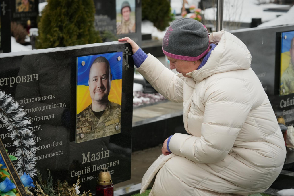 Žena sed&iacute; pri hrobe svojho pr&iacute;buzn&eacute;ho počas spomienkovej bohoslužby pre padl&yacute;ch ukrajinsk&yacute;ch vojakov v ukrajinskom meste Buča. FOTO: TASR/AP
