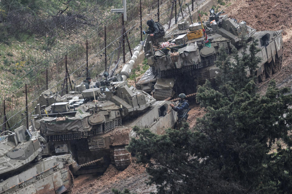 Izraelsk&iacute; vojaci pracuj&uacute; na po&scaron;koden&yacute;ch tankoch uviaznut&yacute;ch v blate na ceste na izraelskej strane hranice s Libanonom. FOTO: Reuters