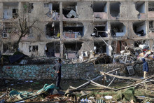 Ľudia stoja pri po&scaron;kodenej budove a trosk&aacute;ch po ir&aacute;nskych raketov&yacute;ch &uacute;tokoch v Dimone v južnom Izraeli. FOTO: Reuters