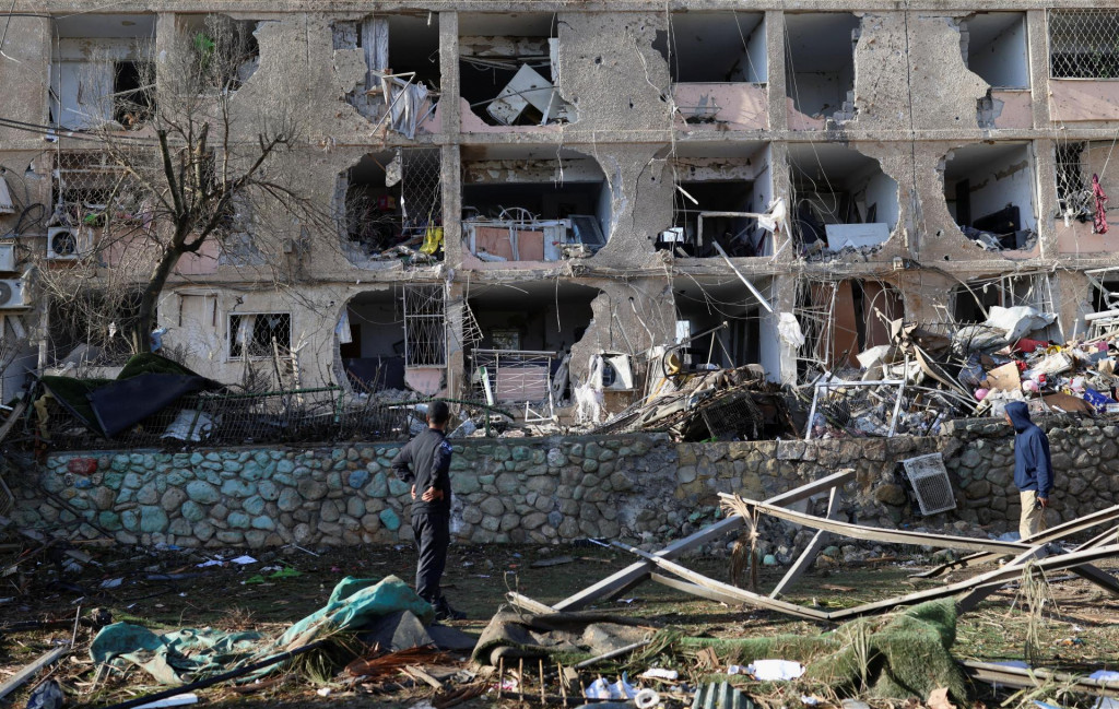 Ľudia stoja pri po&scaron;kodenej budove a trosk&aacute;ch po ir&aacute;nskych raketov&yacute;ch &uacute;tokoch v Dimone v južnom Izraeli. FOTO: Reuters