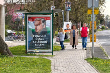 Ľudia kr&aacute;čaj&uacute; okolo predvolebn&eacute;ho plag&aacute;tu maďarskej vl&aacute;dnej strany Fidesz s portr&eacute;tom premi&eacute;ra a predsedu Fideszu Viktora Orb&aacute;na s n&aacute;pisom &rdquo;Zomknime sa proti vojne!&rdquo;. FOTO: TASR/AP