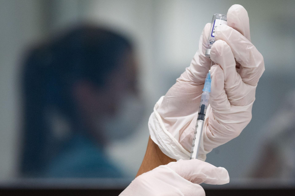 Na arch&iacute;vnej sn&iacute;mke z 25. novembra 2021 žena naťahuje z ampulky do injekčnej striekačky vakc&iacute;nu proti covidu.