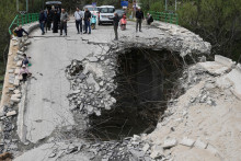 Vys&iacute;dlen&iacute; obyvatelia kr&aacute;čaj&uacute; cez zničen&yacute; most počas n&aacute;vratu domov neďaleko mesta S&uacute;r na juhu Libanonu. FOTO: TASR/AP