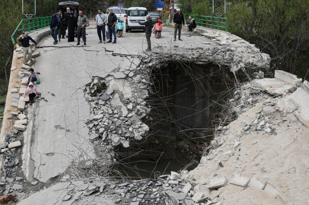 Vys&iacute;dlen&iacute; obyvatelia kr&aacute;čaj&uacute; cez zničen&yacute; most počas n&aacute;vratu domov neďaleko mesta S&uacute;r na juhu Libanonu. FOTO: TASR/AP