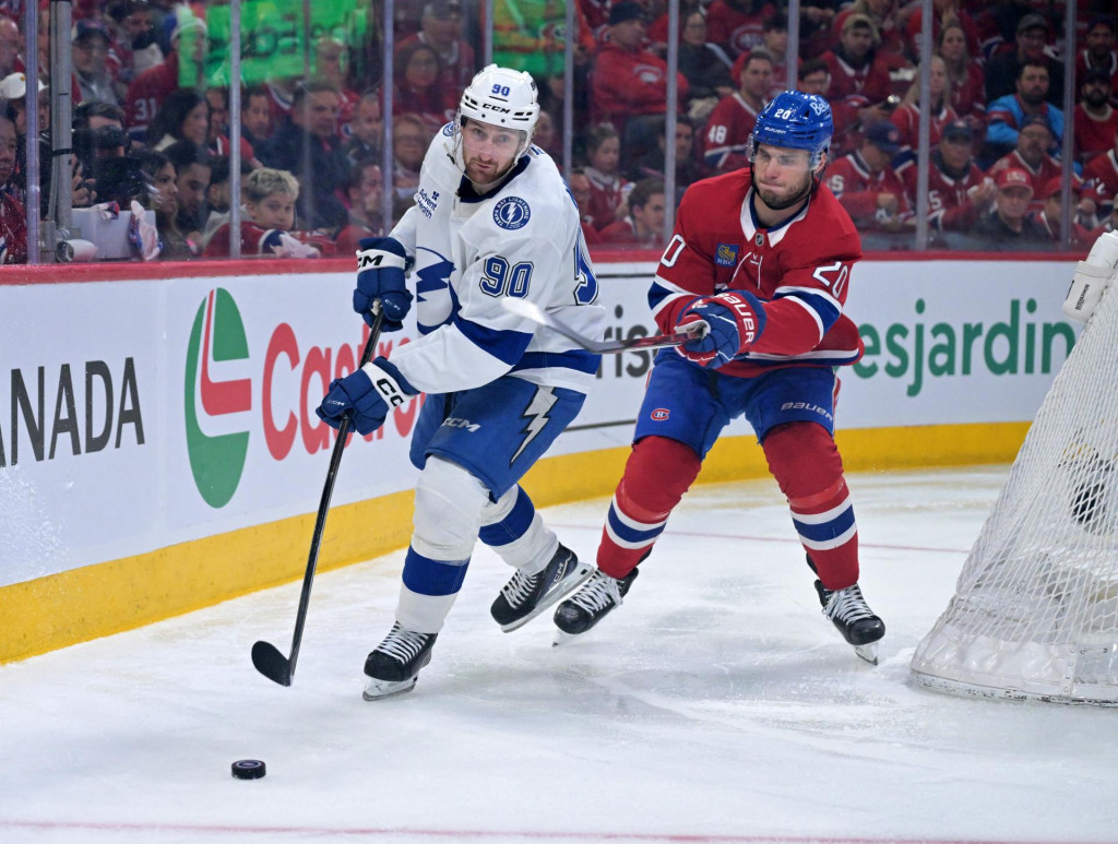 Obranca Tampa Bay Lightning J.J. Moser rozohr&aacute;va puk a &uacute;točn&iacute;k Montreal Canadiens Juraj Slafkovsk&yacute; rob&iacute; forček. FOTO: Reuters/Eric Bolte-Imagn Images