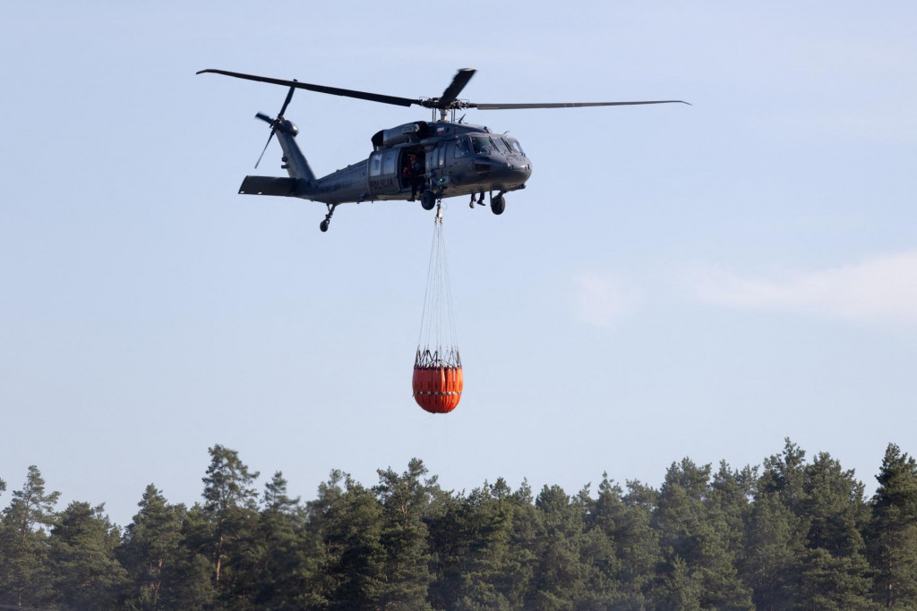 Vrtuľn&iacute;k prepravuje vodu počas hasenia lesn&eacute;ho požiaru neďaleko Jozefowa v Poľsku. FOTO: Reuters/Agencja Wyborcza.pl