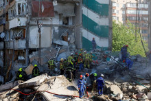 Z&aacute;chran&aacute;ri pracuj&uacute; na mieste bytov&eacute;ho domu po&scaron;koden&eacute;ho počas rusk&yacute;ch &uacute;tokov na Kyjev. FOTO: Reuters