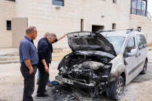 Ľudia kontroluj&uacute; po&scaron;koden&eacute; auto, ktor&eacute; podľa Palest&iacute;nčanov podp&aacute;lili izraelsk&iacute; osadn&iacute;ci neďaleko Birzeitu na Izraelom okupovanom Z&aacute;padnom brehu Jord&aacute;nu. FOTO: Reuters