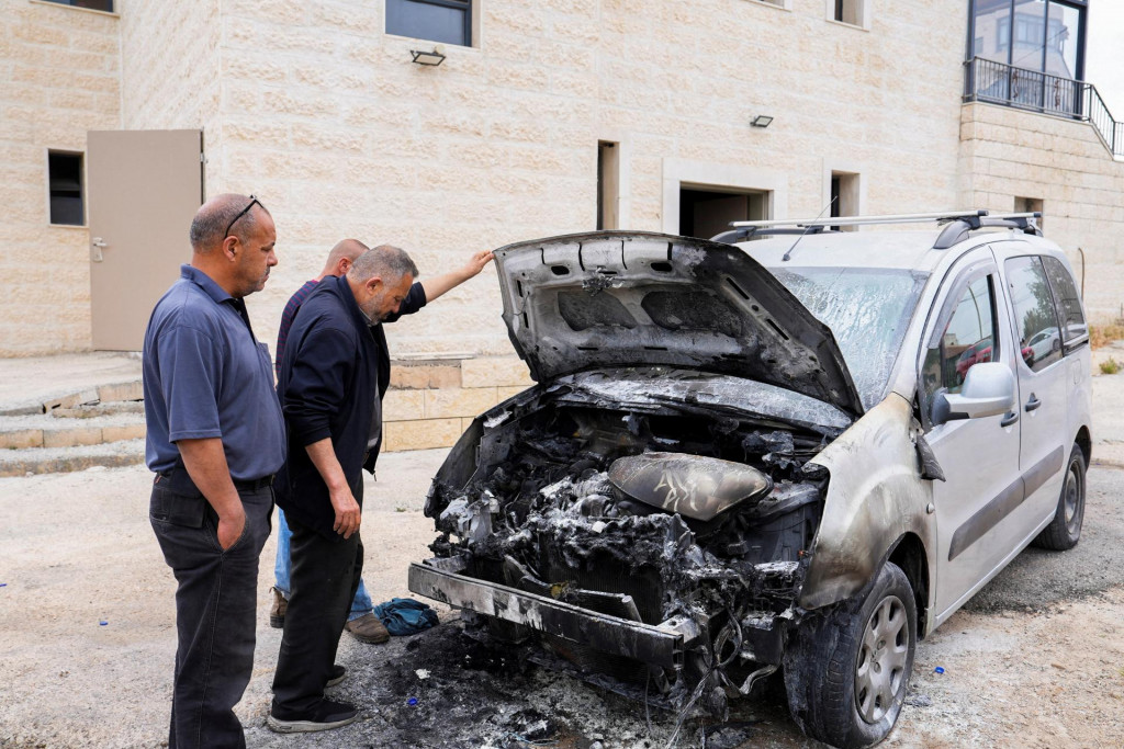 Ľudia kontroluj&uacute; po&scaron;koden&eacute; auto, ktor&eacute; podľa Palest&iacute;nčanov podp&aacute;lili izraelsk&iacute; osadn&iacute;ci neďaleko Birzeitu na Izraelom okupovanom Z&aacute;padnom brehu Jord&aacute;nu. FOTO: Reuters