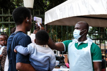 Pracovn&iacute;k nemocnice meria teplotu osob&aacute;m pred vstupom do nemocnice v ugandskom meste Kampala v sobotu 16. m&aacute;ja 2026. FOTO: TASR/AP
