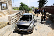 Ľudia sa zhromažďuj&uacute; pri po&scaron;kodenom aute, ktor&eacute; podľa Palest&iacute;nčanov podp&aacute;lili izraelsk&iacute; osadn&iacute;ci v Halhule neďaleko Hebronu na Izraelom okupovanom Z&aacute;padnom brehu Jord&aacute;nu. FOTO: Reuters