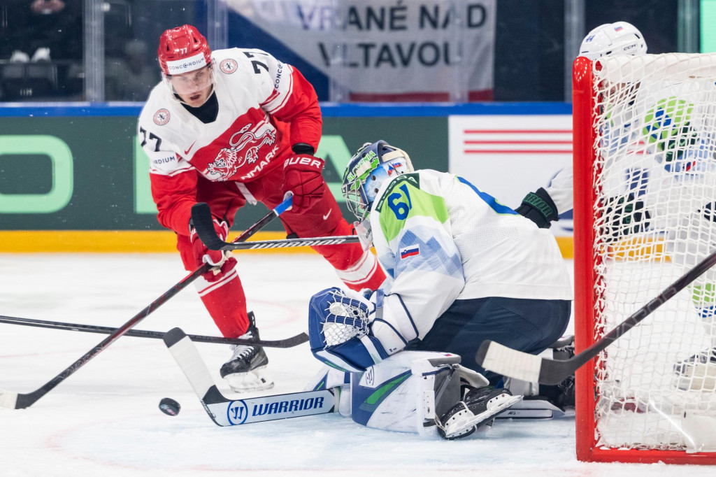 D&aacute;nsky hr&aacute;č Mathias From (vľavo) bojuje o puk so slovinsk&yacute;m brank&aacute;rom Luk&aacute;&scaron;om Hor&aacute;kom počas z&aacute;pasu z&aacute;kladnej B-skupiny D&aacute;nsko - Slovinsko na MS v ľadovom hokeji vo Fribourgu v sobotu 23. m&aacute;ja 2026. FOTO: TASR/AP