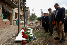 Členovia diplomatick&yacute;ch misi&iacute; na Ukrajine klad&uacute; kvety na miesto zasiahnutia bytov&eacute;ho domu počas ned&aacute;vnych rusk&yacute;ch &uacute;tokov v Kyjeve. FOTO: Reuters