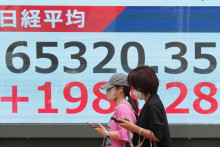 Ľudia kr&aacute;čaj&uacute; okolo elektronickej tabule, ktor&aacute; zobrazuje japonsk&yacute; index Nikkei 225 v Tokiu 25. m&aacute;ja 2026. FOTO: TASR/AP