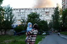 Žena drž&iacute; dieťa na mieste rusk&yacute;ch raketov&yacute;ch a bezpilotn&yacute;ch &uacute;tokov uprostred rusk&eacute;ho &uacute;toku na Ukrajinu v Kyjeve na Ukrajine 2. j&uacute;na 2026. FOTO: REUTERS