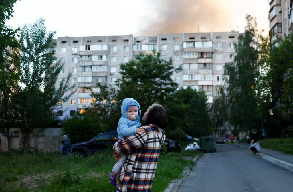 Žena drž&iacute; dieťa na mieste rusk&yacute;ch raketov&yacute;ch a bezpilotn&yacute;ch &uacute;tokov uprostred rusk&eacute;ho &uacute;toku na Ukrajinu v Kyjeve na Ukrajine 2. j&uacute;na 2026. FOTO: REUTERS