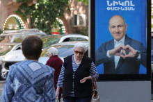 Ľudia v Jerevane prech&aacute;dzaj&uacute; okolo volebn&yacute;ch transparentov s portr&eacute;tmi premi&eacute;ra Nikola Pa&scaron;injana zo strany Občianska zmluva pred parlamentn&yacute;mi voľbami. FOTO: Reuters