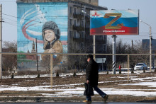 FILE PHOTO: A pedestrian walks near a board, which displays the symbol &rdquo;Z&rdquo; in support of the Russian armed forces involved in the country&lsquo;s military campaign in Ukraine, in the settlement of Chernomorskoye, Crimea, February 11, 2023. A sign on the board reads: &rdquo;We don&lsquo;t abandon our people&rdquo;. REUTERS/Alexey Pavlishak FOTO: ALEXEY PAVLISHAK