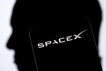 Logo firmy SpaceX v popred&iacute; siluety Elona Muska. SpaceX je najv&auml;č&scaron;ou prvou verejnou ponukou akci&iacute; v burzovej hist&oacute;rii. FOTO: REUTERS
