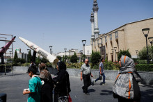 Ľudia kr&aacute;čaj&uacute; vedľa symbolickej makety ir&aacute;nskej rakety na ulici v Teher&aacute;ne. FOTO: Reuters
