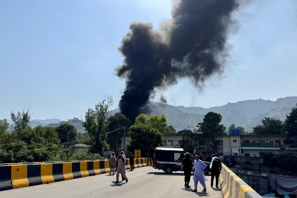 Ľudia a pol&iacute;cia sa zhromažďuj&uacute; neďaleko, zatiaľ čo sa dym val&iacute; z miesta, kde sa zr&uacute;til vrtuľn&iacute;k Mi-17 pakistansk&eacute;ho arm&aacute;dneho letectva. FOTO: Reuters