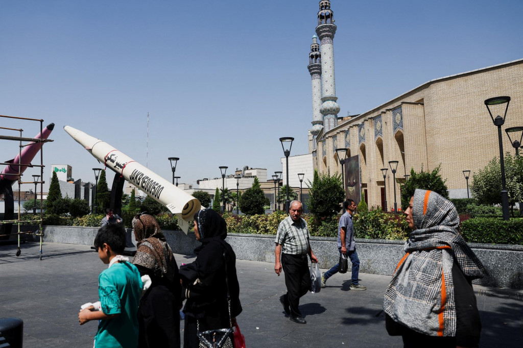 Ľudia kr&aacute;čaj&uacute; vedľa symbolickej makety ir&aacute;nskej rakety na ulici v Teher&aacute;ne. FOTO: Reuters