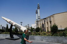 Muž kr&aacute;ča vedľa symbolickej makety ir&aacute;nskej rakety na ulici v Teher&aacute;ne. FOTO: Reuters/WANA