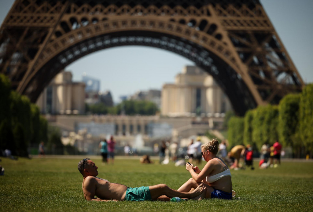 Na arch&iacute;vnej sn&iacute;mke z 27. m&aacute;ja 2026 ľudia sa opaľuj&uacute; neďaleko Eiffelovej veže v Par&iacute;ži. FOTO: TASR/AP