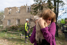 Žena drž&iacute; mačku, ktor&uacute; na&scaron;la počas z&aacute;chran&aacute;rskych pr&aacute;c v zničenej obytnej budove po ruskom raketovom &uacute;toku. FOTO: TASR/AP
