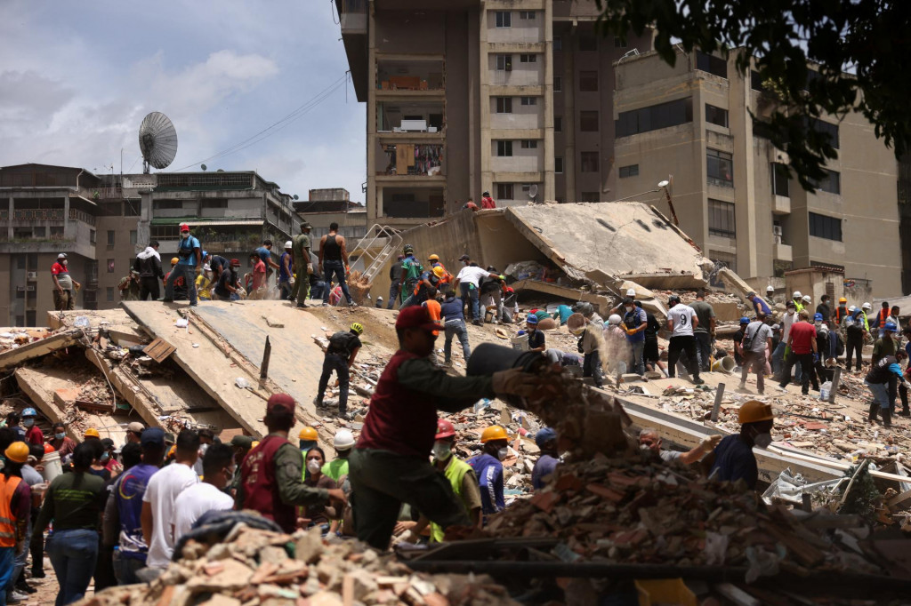Ľudia hľadaj&uacute; obete v trosk&aacute;ch zr&uacute;tenej budovy po zemetraseniach v Caracase vo Venezuele. FOTO: Reuters
