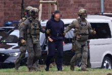 Pol&iacute;cia eskortuje Serhiia K. k vrtuľn&iacute;ku po vypočut&iacute; s nemeck&yacute;m feder&aacute;lnym prokur&aacute;torom. FOTO: REUTERS
