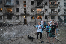 Ľudia sa pozeraj&uacute; na kr&aacute;ter pred zhorenou obytnou budovou po ruskom raketovom &uacute;toku v Kyjeve. FOTO: TASR/AP