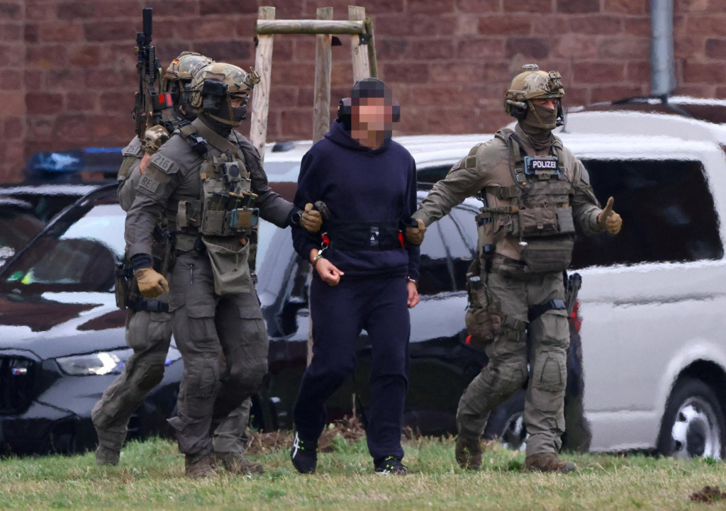 Pol&iacute;cia eskortuje Serhiia K. k vrtuľn&iacute;ku po vypočut&iacute; s nemeck&yacute;m feder&aacute;lnym prokur&aacute;torom. FOTO: REUTERS
