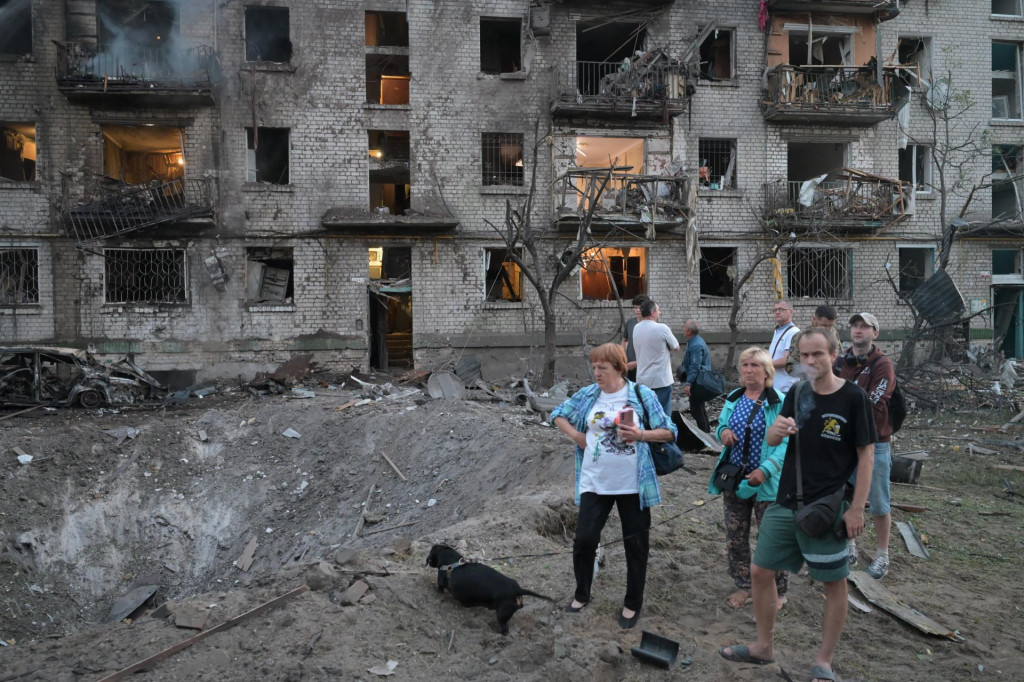 Ľudia sa pozeraj&uacute; na kr&aacute;ter pred zhorenou obytnou budovou po ruskom raketovom &uacute;toku v Kyjeve. FOTO: TASR/AP