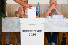 Na sn&iacute;mke volič vhadzuje ob&aacute;lku s hlasovac&iacute;m l&iacute;stkom do volebnej schr&aacute;nky vo volebnej miestnosti počas referenda v obci Kov&aacute;lovec v okrese Skalica v sobotu 4. j&uacute;la 2026. FOTO: TASR/Martin Medňansk&yacute;